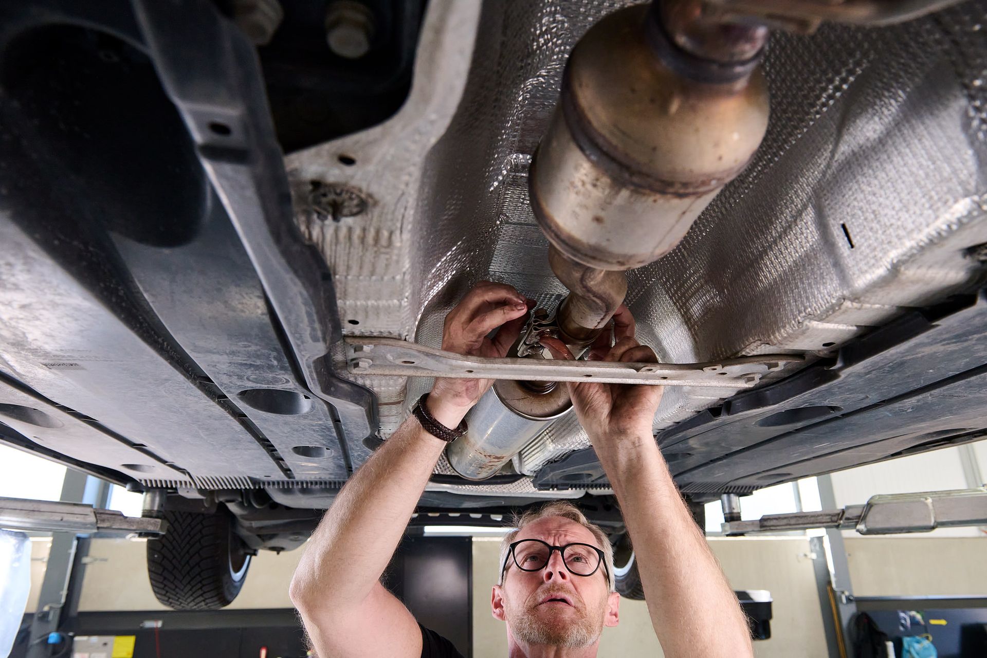 CRC auto technieker die werkt aan uitlaat