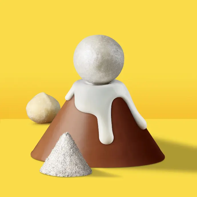 Maison Macolat chocolate enrobed macademia nut on a brown cone on a yellow background