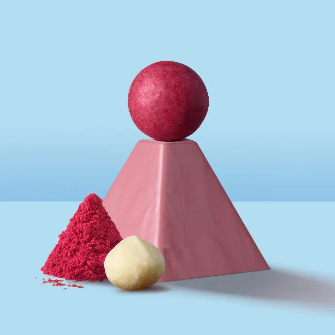 Red Macolat chocolate ball on a Ruby chocolate pyramid on a light blue background