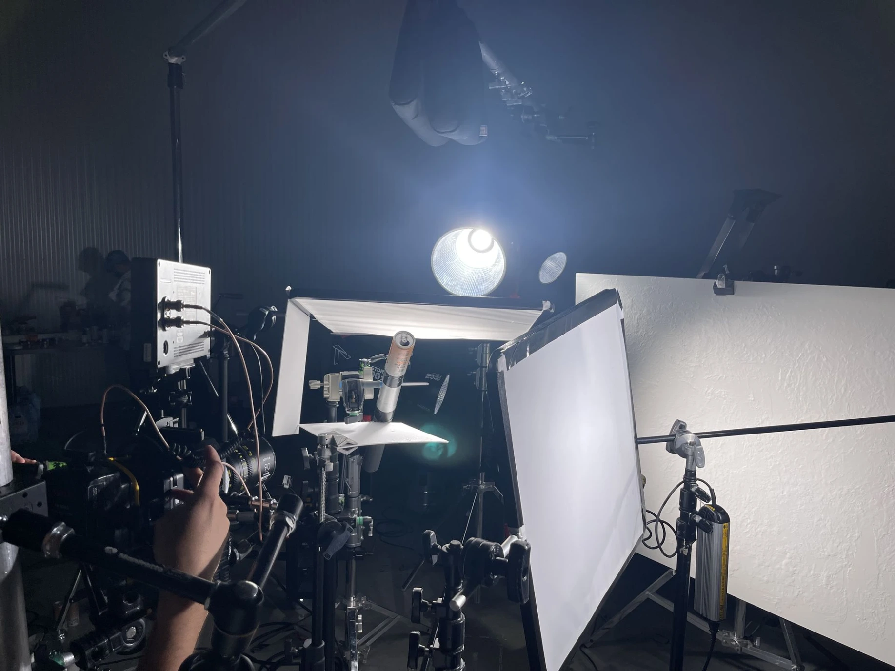 Behind-the-scenes at Studio Ballena — the Camerabotics CRX1440 motion control rig positioned over a small product on a tabletop set, surrounded by diffusion panels, lighting and a technician's hand reaching in to adjust the rig.